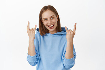 Awesome party. Carefree teen girl, woman showing tongue, winking with horns, heavy metal rock gesture, enjoying event or concern, like smth cool, white background