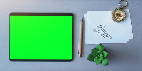Big tablet with green screen on a laptop. The concept for freelancing, working from the beach, vacations, holidays, and remote working and home office.