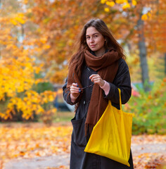 happy girl in autumn in the park, with yellow eco shopping bag