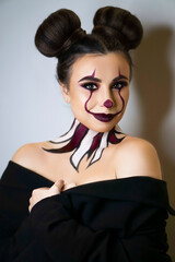 close-up portrait female clown woman scary crazy smiling laugh. On light vertical backdrop. Art...