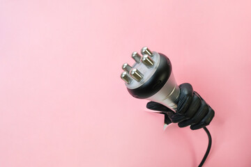 RF lifting hardware massage on a pink background. hand in a black glove with an apparatus. - obrazy, fototapety, plakaty