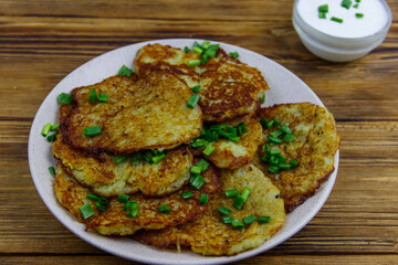 Potato pancakes with sour cream on a wooden table