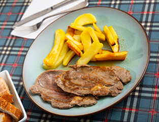 Roasted beef Ternera con patata with potatoes fries on a ceramic plate cooked in a cafe