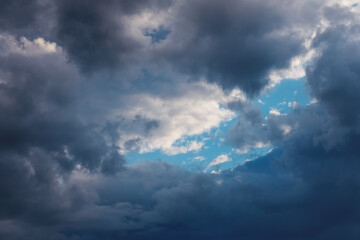 Fototapeta na wymiar Part of blue sky look through frame of dark clouds. Beautiful natural air background.
