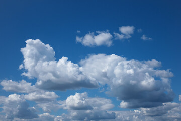 Naklejka na ściany i meble White flocky clouds over blue sky background. Beautiful view of natural scene at sunny day.