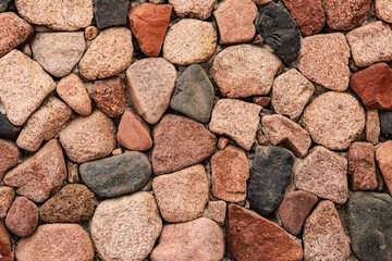 Beautiful Background from natural stones of different colors. Decorative masonry of the wall from large textured stones of various colors. Rustic wall design using natural materials
