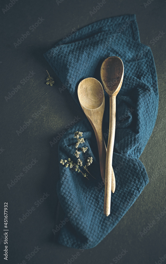 Wall mural Two hand crafted wooden spoons on dark blue kitchen towel. Copy space. Culinary concept