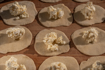 Process of modeling dumplings with cottage cheese filling on cutting board. Pierogi stuffed with curd. Topic - home-made food