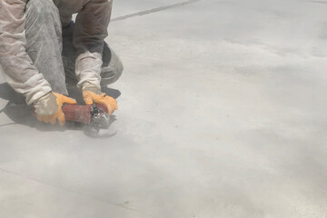 Close up of worker's hands using angle grinder. Removing of bleeding cement. Construction worker grinds concrete making clouds of dust