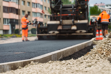 Road paving machine stacking asphalt on the street.