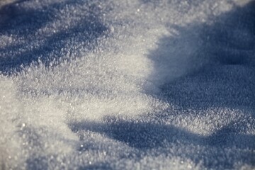 White ice crystals in bright sunlight. Macro photography of ice crystal texture. Snow crystals close-up on a bright frosty winter day. White sparkling snow surface close up. Abstract snowy pattern.