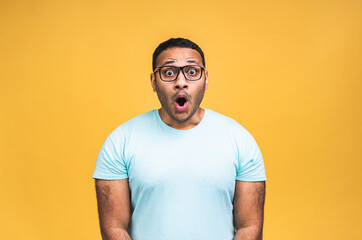 Surprised amazed african american indian man guy in casual isolated over yellow background studio portrait. People lifestyle concept. Mock up copy space. Keeping mouth open.