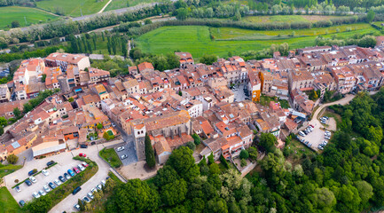 Fototapeta na wymiar Scenic aerial view of small Spanish village of Hostalric in green summer valley at foothills of castle hillock, Girona, Catalonia