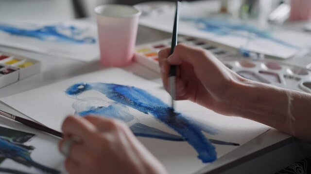 Closeup of a female hands drawing a parrot on a sheet of paper in different colors. Stay home, game concept. Master class in drawing. High quality 4k footage