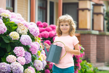 Garden works. Spring gardening. Kid with watering can in garden. Plant and care flowers.