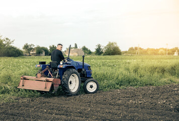 A farmer is driving a tractor across the field. Mill grinding machine for soil. Land cultivation....