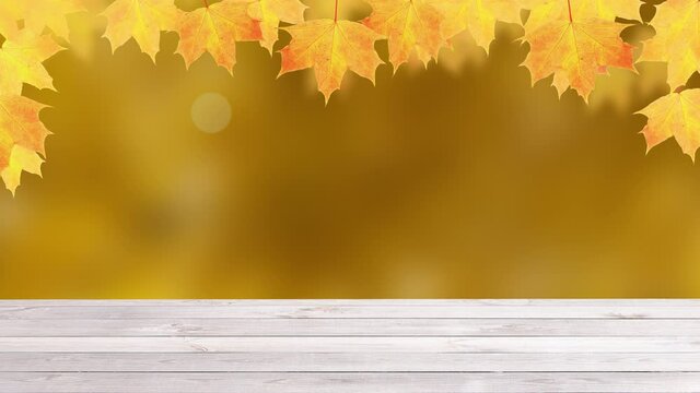 Yellow-orange maple leaves and emty wooden table on autumn nature background