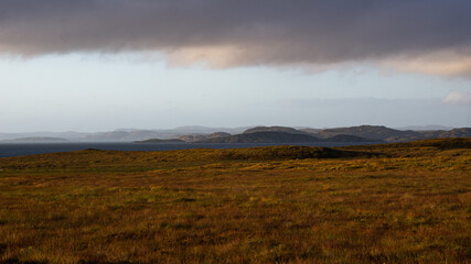 Scottish landscape at sunset with field, sea, mountains and clouds