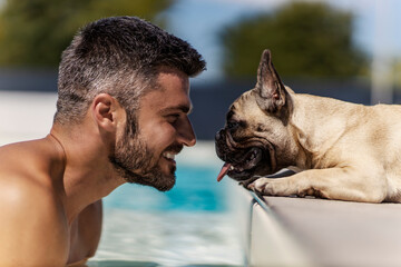 The dog and its owner are at the pool A smiling middle-aged man with a handsome face refreshes...