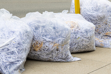 White plastic bags of shredded paper on the curb for recycling pick up.