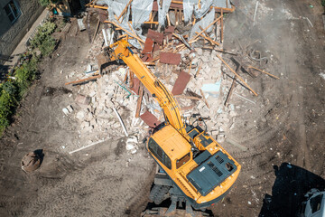 Process of demolition of old building dismantling aerial view. Excavator breaking house. Destruction of dilapidated housing for new development.