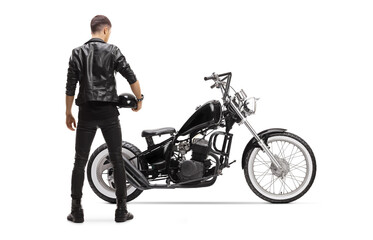 Obraz na płótnie Canvas Rear view of a biker in a leather jacket with a chopper holding a helmet