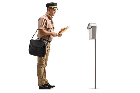 Full length profile shot of a mailman putting a letter in a mailbox
