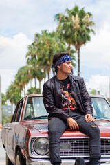 Fototapeta na wymiar Young rocker man on his old car on the street