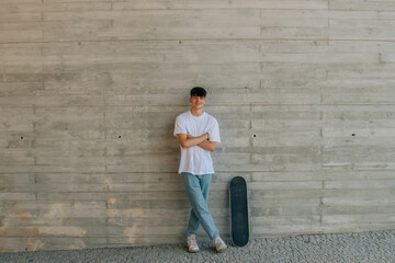 teen boy with skateboard on wall with copy space