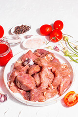 Raw pork pieces, tomatoes, spices, and herbs