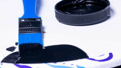 A blue paintbrush and black paint