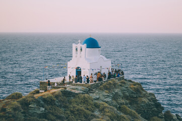 Fototapeta na wymiar Church on the rock. Located in Sifnos island. One of the most famous spots in Greece. This shot is taken during a traditional wedding.
