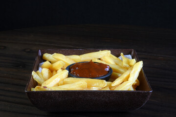 delicious french fries with pepper sauce and tomato inside the bowl isolated on black background.