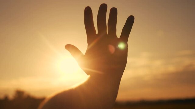 girl stretches out her hand in the sun. faith in god dream a religion concept sunlight. hand in sun the close-up silhouette dream of happiness