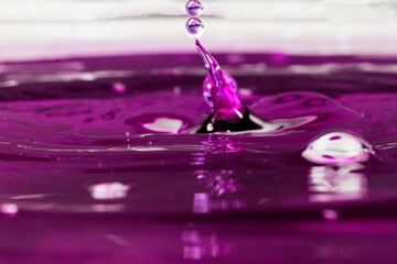 Pingo e gota em superfície sobre liquido roxo.