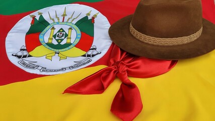 Hat, red gaucho scarf and State Flag of Rio Grande do Sul - Brazil, on the table. Decoration to commemorate the traditional Week in southern Brazil. Farroupilha from the Gauchos.