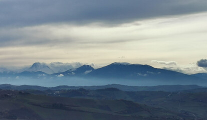 Fototapeta na wymiar Nuvole ovattate sopra le cime innevate dei monti Appennini
