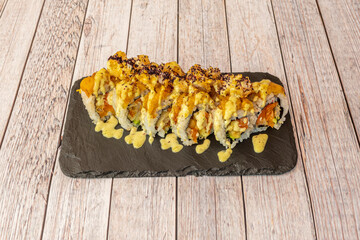 Sushi uramaki tiger with prawns and crispy with sauce on black slate plate