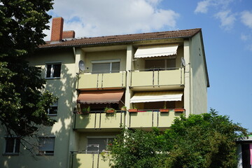 Grünes Mietshaus mit Markisen und Balkons im Sommer bei Sonnenschein in einer Wohnsiedlung an der...