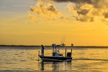 Silhouette of man fishing on a boat at dawn