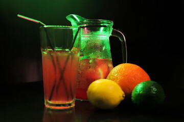 summer refreshing, lemonade drink. mix of fruits. lemon, lime, orange, mint. decanter and glass close up. there are fruits nearby