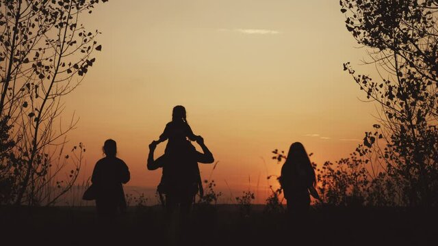 happy family tourists go hiking in park sunset silhouette. adventure travel concept. teamwork. happy family a tourists with backpacks sun hikers go camping. group people teamwork walking park
