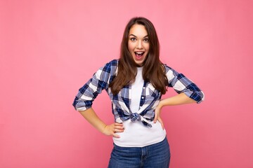 Photo portrait of young beautiful smiling hipster brunette woman in trendy blue and white shirt and jeans clothes. Sexy carefree female person posing isolated near pink wall with empty space in studio