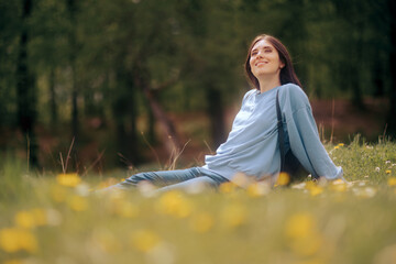 Happy Young Woman Sitting in the Grass Enjoining Nature
