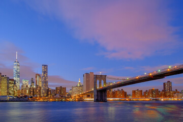 The Brooklyn Bridge at dusk and sundown spanning across the east river between Brooklyn and lower...
