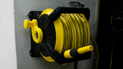 A yellow wall mounted garden water hose reel with sprinkler or sprayer.. Cleaning tool, garden and...