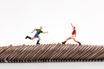 Puppets playing football symbolize competition on coins