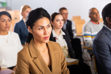 Young woman entrepreneur attending seminar with colleagues in board room