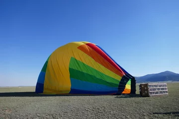 Poster Deflated rainbow colored hot air balloon laying on side © Adventuring Dave