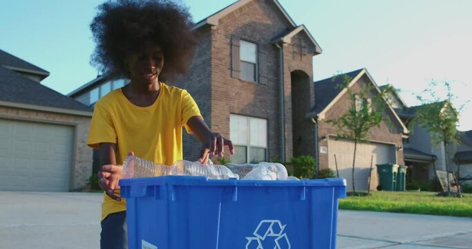 African American adolescence placing plastic bottles in recycle bin